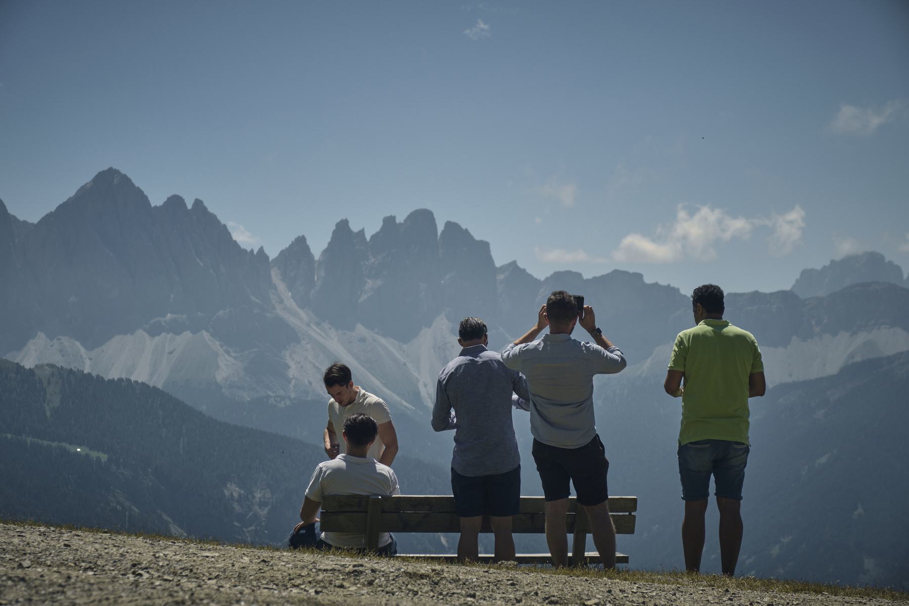 Vier Teilnehmer sitzen auf einer Bank und blicken auf das Bergpanorama.