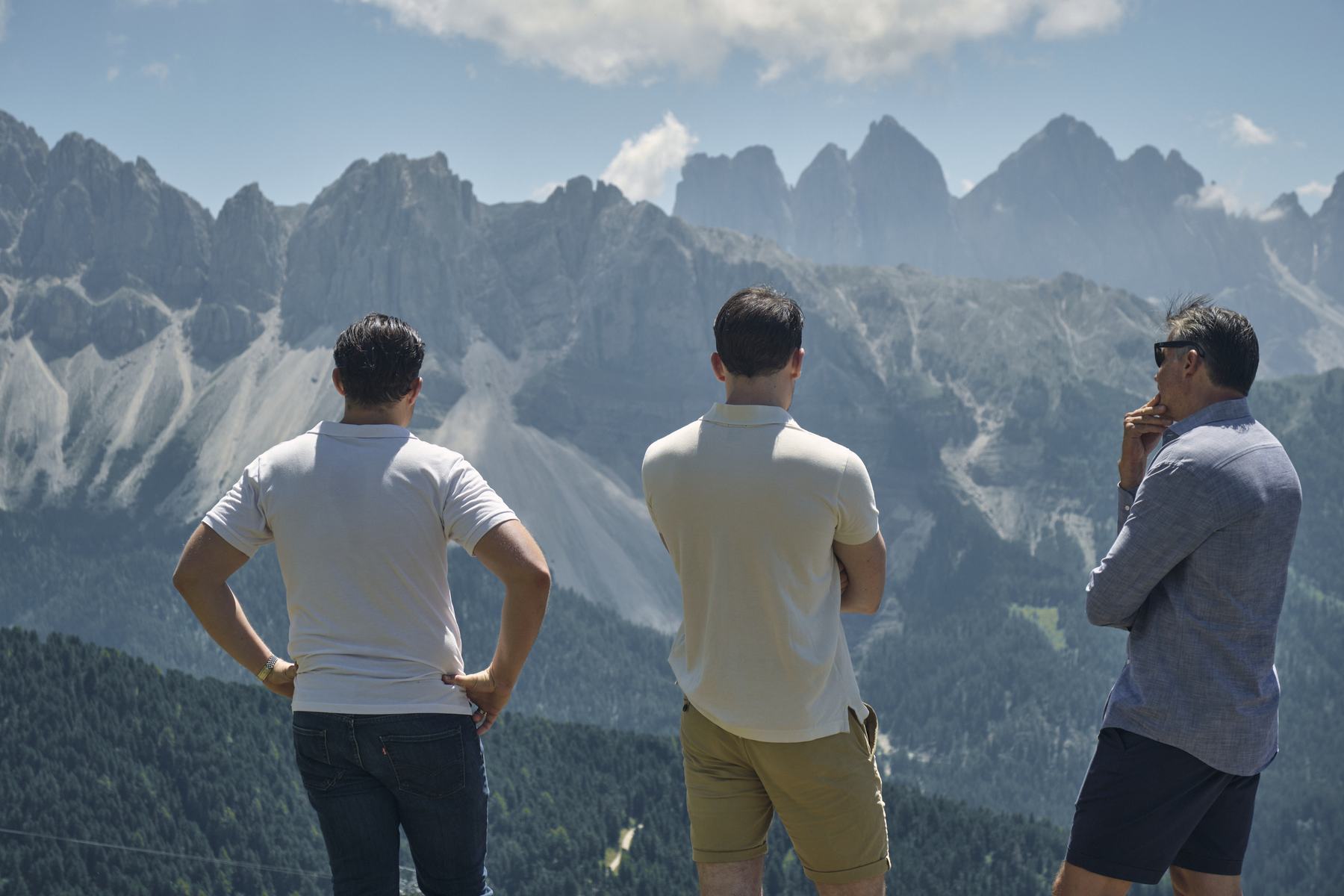 Drei Teilnehmer stehen auf einem Gipfel und blicken auf das Dolomitenpanorama.